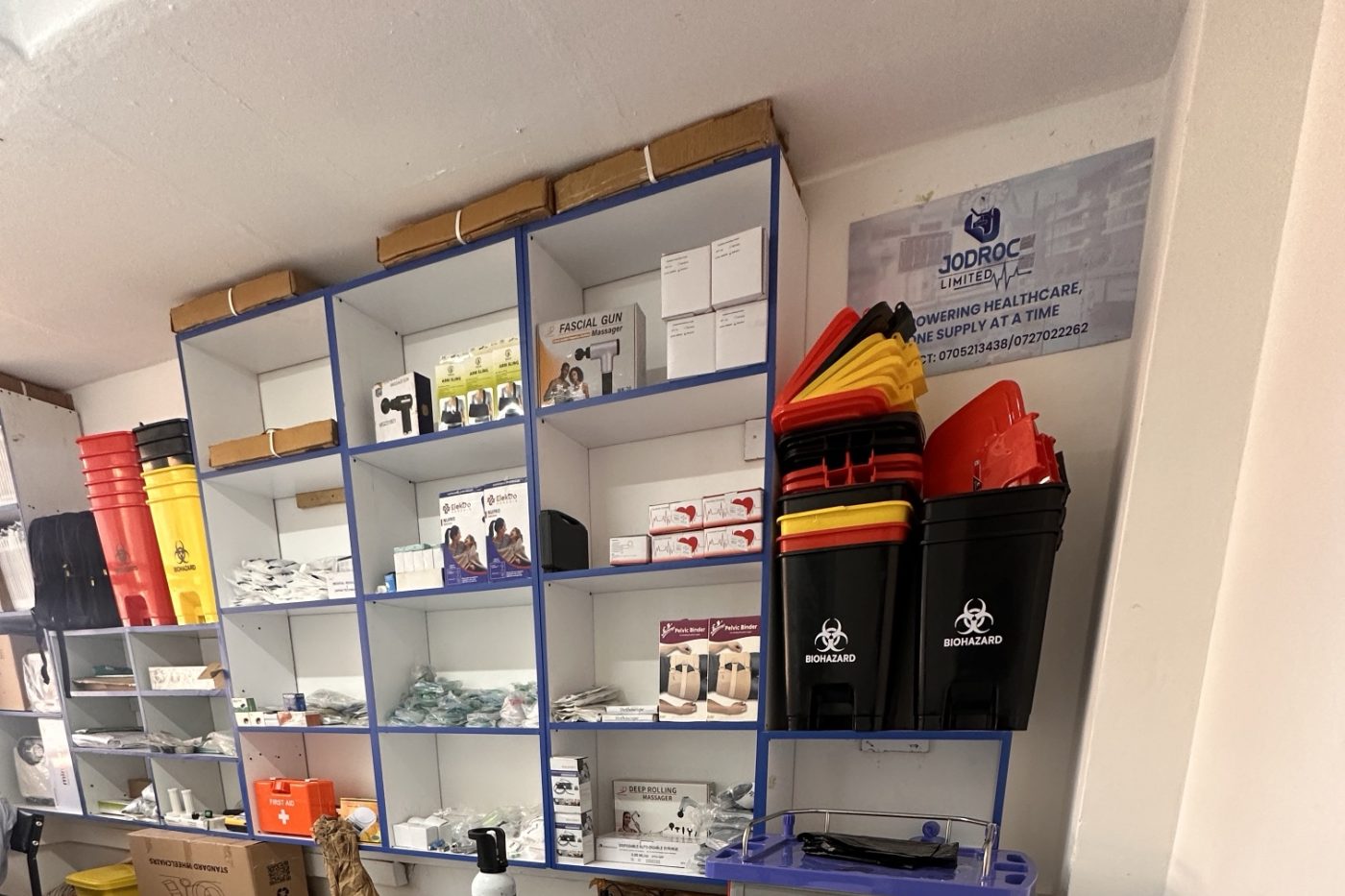 Medical equipment shelving at Jodroc Limited, with biohazard bins and an emergency trolley