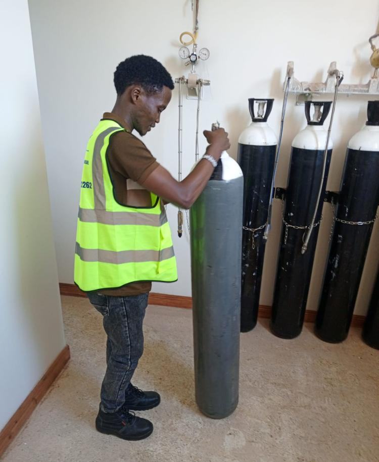 Engineer fitting a cylinder to the wall-mounted gas rail